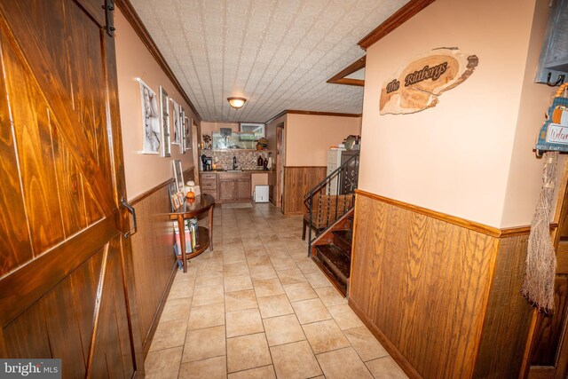 hallway featuring a wainscoted wall, an ornate ceiling, stairs, and wooden walls