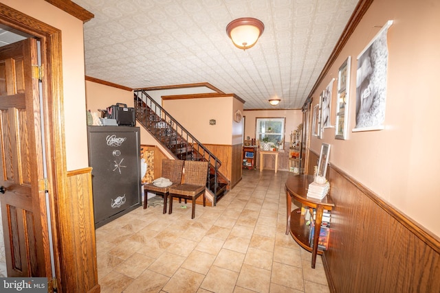 entrance foyer featuring stairs, wooden walls, an ornate ceiling, and wainscoting