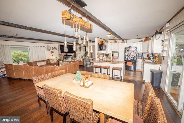 dining area featuring beam ceiling, dark wood-style floors, and a fireplace