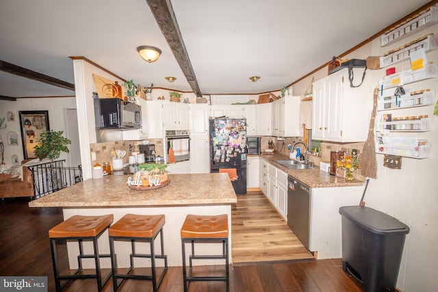 kitchen featuring black appliances, a sink, backsplash, dark wood finished floors, and a peninsula