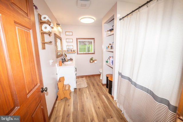 full bathroom with a shower with shower curtain, toilet, wood finished floors, and vanity