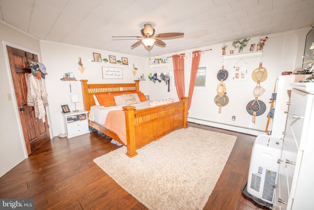 bedroom featuring a baseboard heating unit, hardwood / wood-style floors, a ceiling fan, and ornamental molding