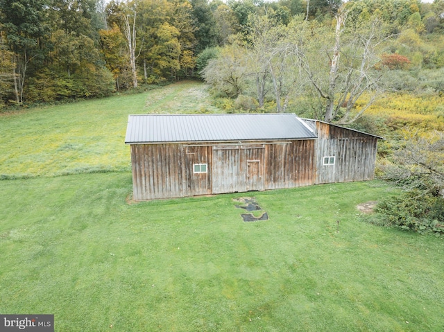 view of pole building with a lawn and a view of trees