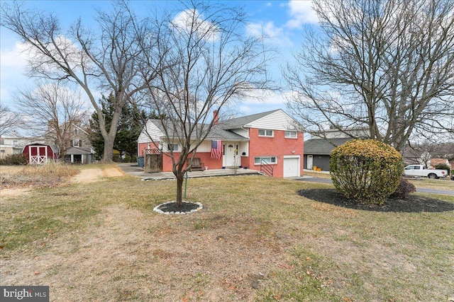 tri-level home with a garage, a chimney, a front lawn, and brick siding