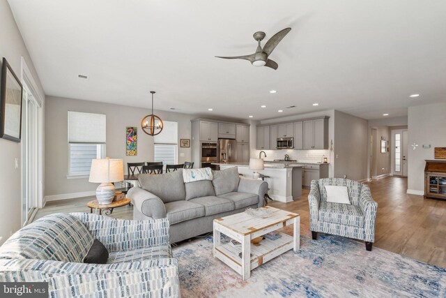 living area featuring recessed lighting, baseboards, ceiling fan, and light wood-style floors