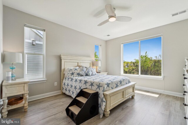 bedroom with light wood-type flooring, baseboards, and multiple windows