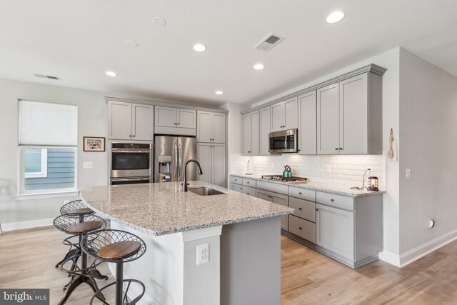 kitchen featuring appliances with stainless steel finishes, a sink, visible vents, baseboards, and gray cabinetry