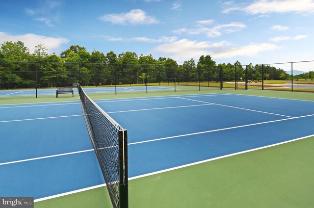 view of tennis court featuring fence and community basketball court