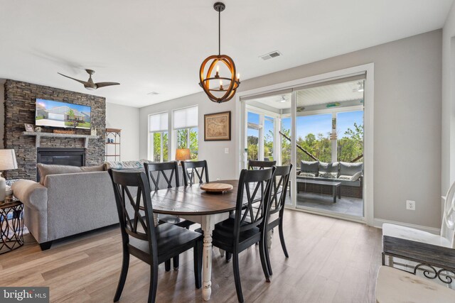 dining space featuring a fireplace, a chandelier, light wood-style flooring, and visible vents
