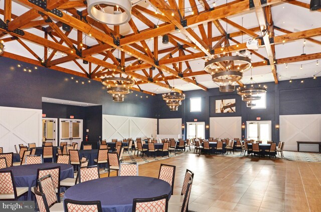 dining space with an inviting chandelier, high vaulted ceiling, a decorative wall, and beam ceiling