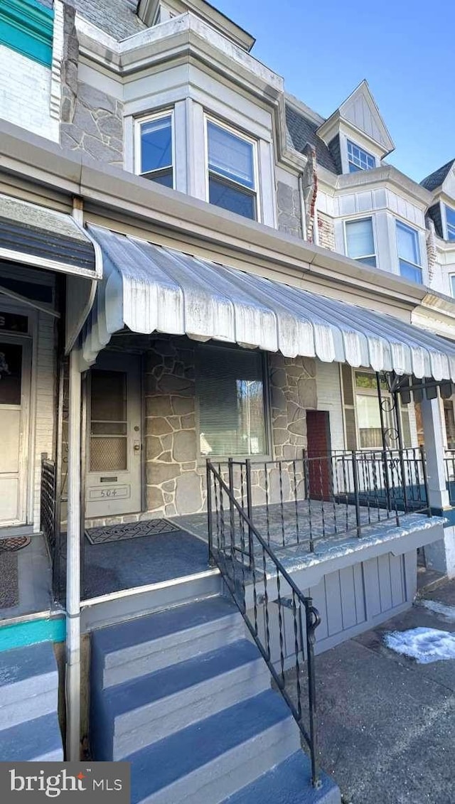 view of front of home featuring covered porch and stone siding