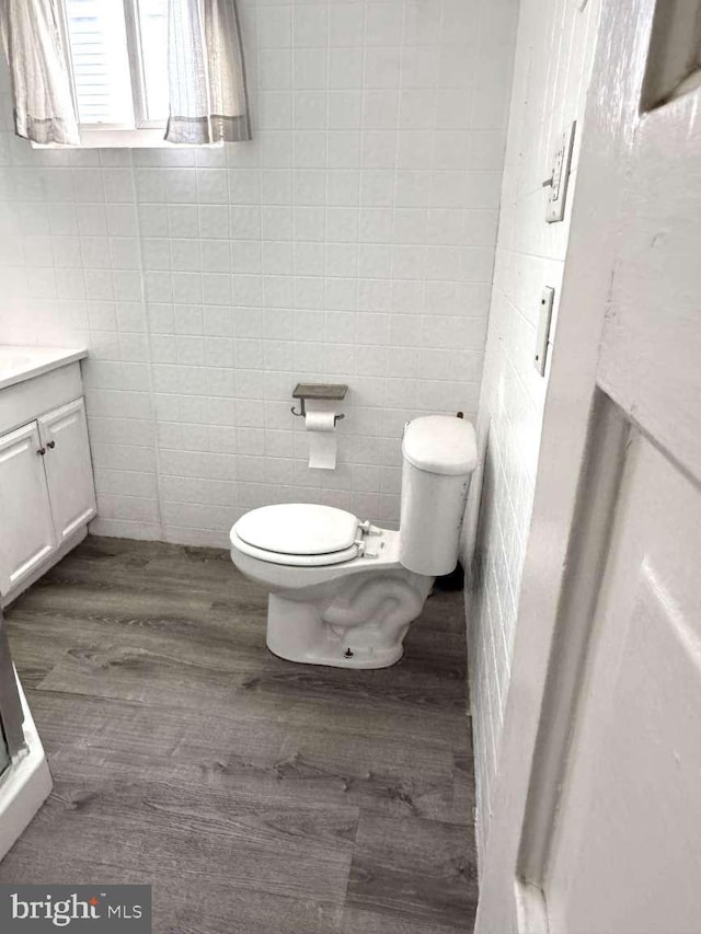 bathroom featuring wood finished floors, vanity, toilet, and tile walls