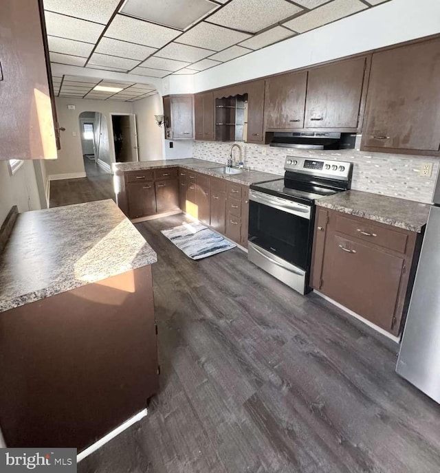 kitchen featuring arched walkways, tasteful backsplash, appliances with stainless steel finishes, a sink, and under cabinet range hood