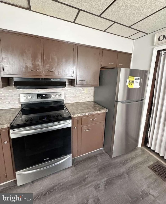 kitchen featuring dark wood finished floors, stainless steel appliances, visible vents, backsplash, and under cabinet range hood