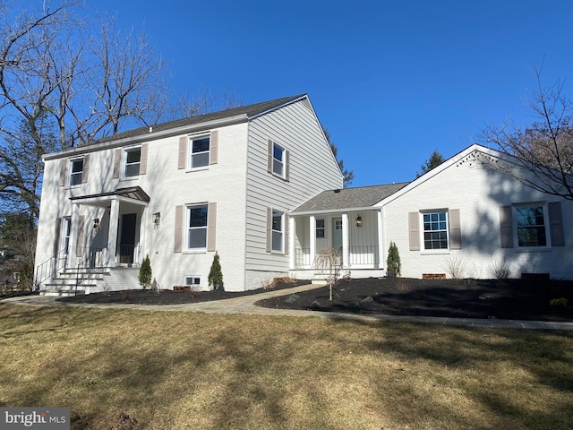 colonial house with a front lawn and brick siding