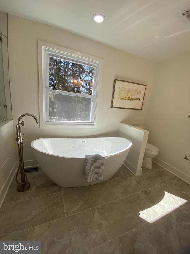 bathroom featuring recessed lighting, visible vents, a freestanding bath, toilet, and baseboards