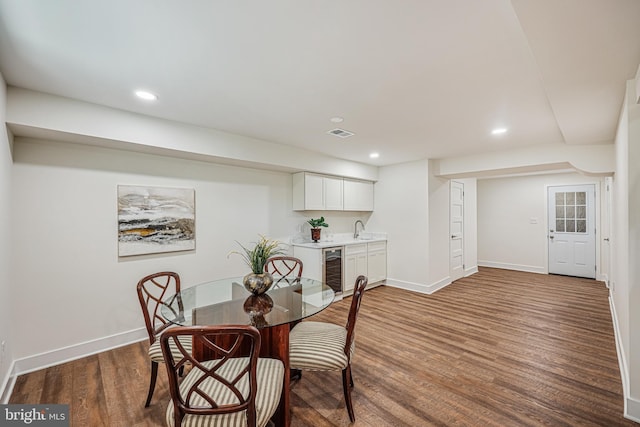 dining room featuring baseboards, visible vents, wine cooler, wood finished floors, and recessed lighting