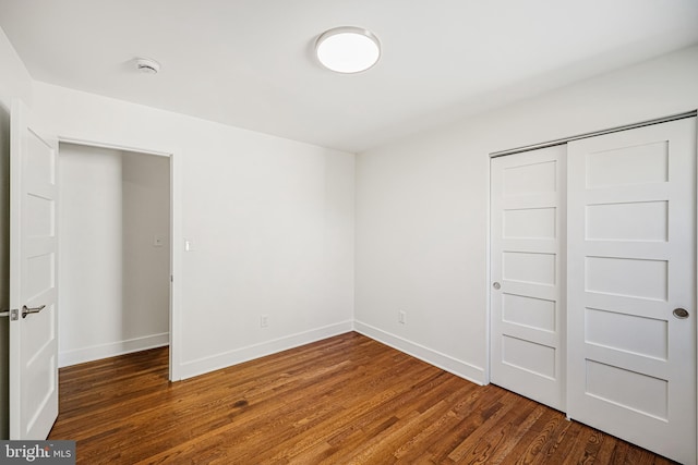 unfurnished bedroom with a closet, baseboards, and wood finished floors