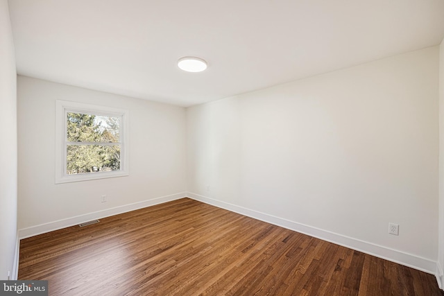 empty room with visible vents, baseboards, and wood finished floors