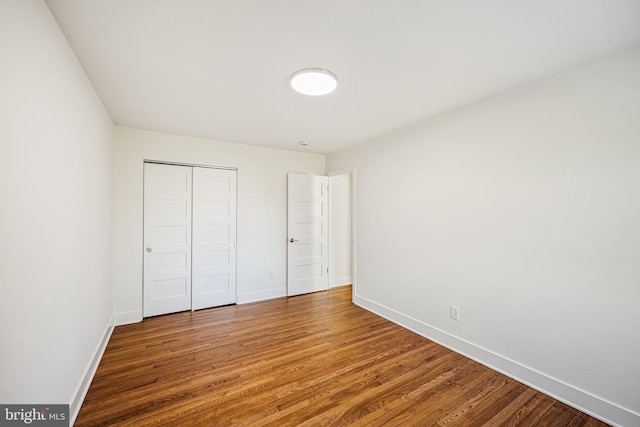 unfurnished bedroom with a closet, baseboards, and wood finished floors