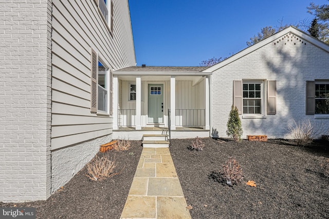 doorway to property featuring brick siding and a porch