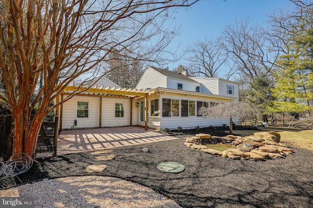 view of front of home featuring a patio area, a chimney, a pergola, and a sunroom