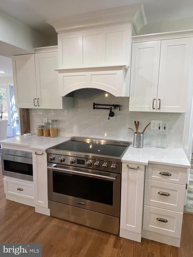 kitchen featuring appliances with stainless steel finishes, white cabinets, decorative backsplash, and dark wood-style floors