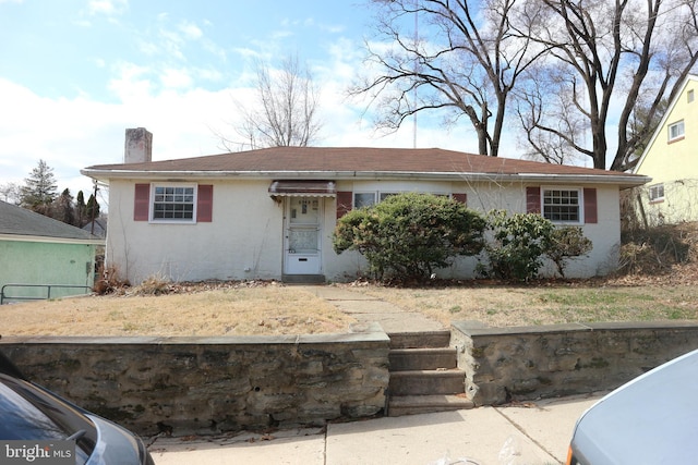 view of front of home with a chimney and stucco siding