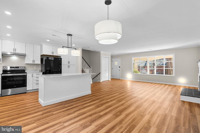 kitchen featuring under cabinet range hood, stainless steel electric stove, open floor plan, black fridge, and white cabinetry