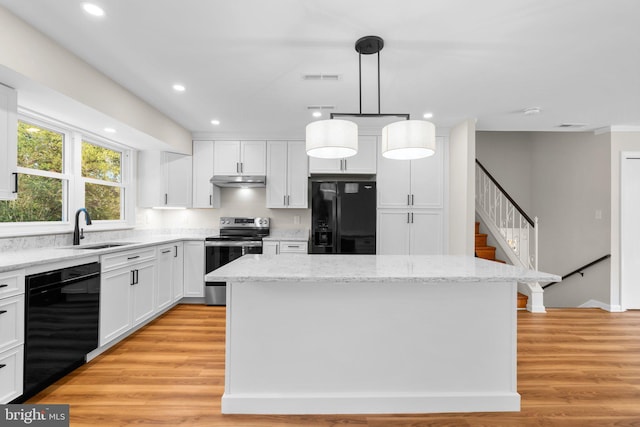 kitchen with a center island, under cabinet range hood, light wood-style flooring, black appliances, and a sink