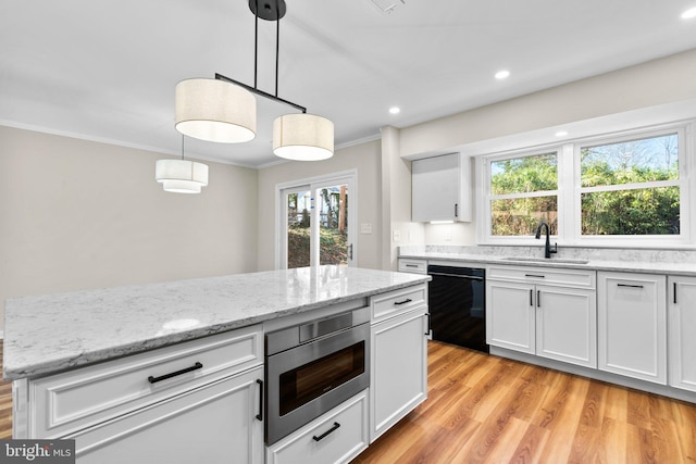 kitchen featuring stainless steel microwave, crown molding, dishwasher, white cabinets, and a sink