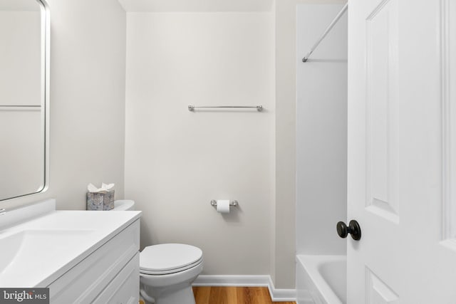 full bathroom with toilet, vanity, baseboards, and wood finished floors