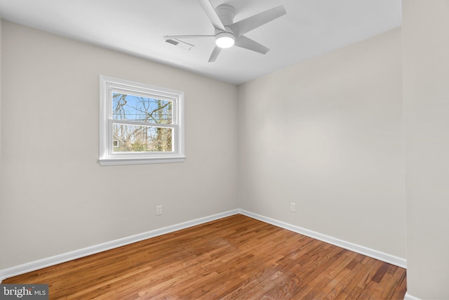 empty room featuring ceiling fan, visible vents, baseboards, and hardwood / wood-style floors