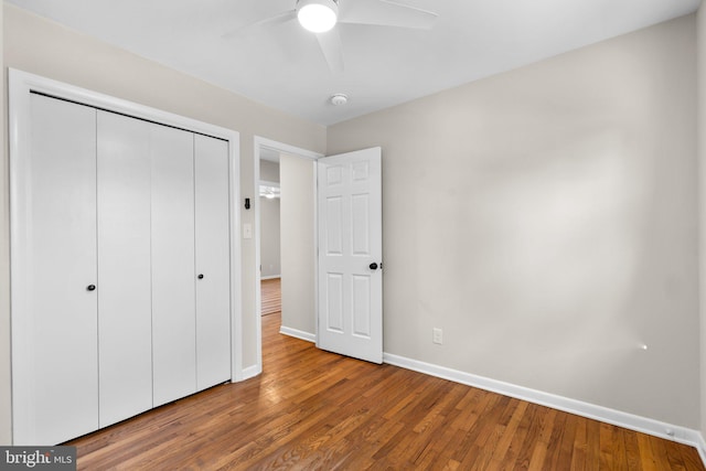 unfurnished bedroom with a closet, a ceiling fan, baseboards, and wood finished floors