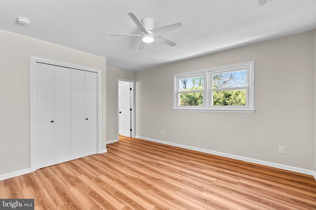 unfurnished bedroom with baseboards, light wood-type flooring, and a closet