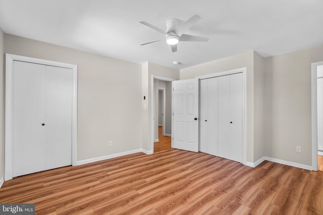 unfurnished bedroom featuring two closets, light wood-type flooring, and baseboards