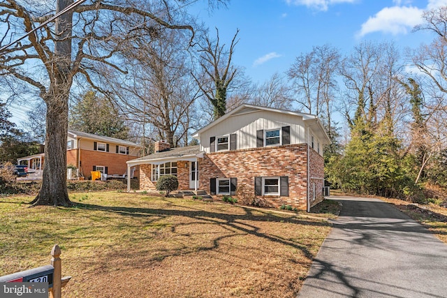 tri-level home featuring aphalt driveway, brick siding, and a front yard