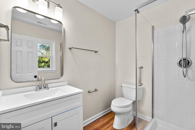 bathroom featuring visible vents, toilet, a stall shower, wood finished floors, and vanity