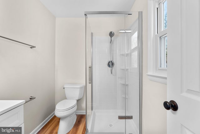 full bathroom with a shower stall, baseboards, toilet, wood finished floors, and vanity