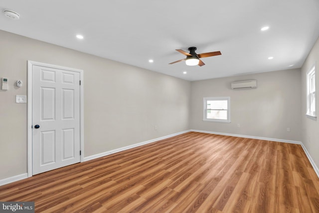 unfurnished room featuring a wall mounted air conditioner, baseboards, recessed lighting, and light wood finished floors