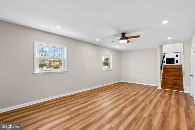 unfurnished room with light wood-style flooring, a ceiling fan, recessed lighting, stairway, and baseboards