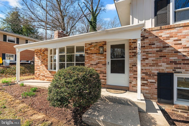 doorway to property with brick siding and a chimney