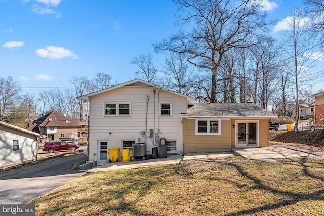 rear view of house with a patio, central air condition unit, and a lawn