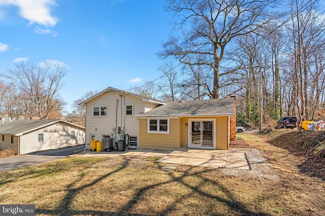 back of house with a patio, roof with shingles, a yard, central AC, and a chimney