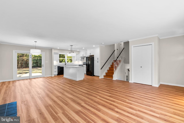 unfurnished living room featuring light wood finished floors, crown molding, stairs, and baseboards