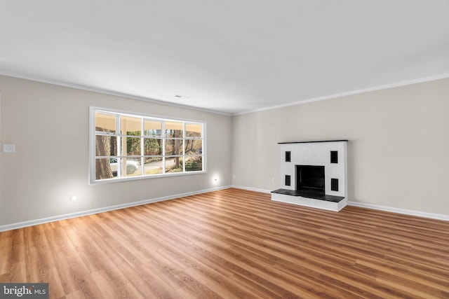 unfurnished living room with a fireplace, light wood-type flooring, baseboards, and crown molding