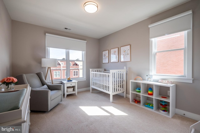 bedroom with a nursery area, carpet flooring, baseboards, and visible vents