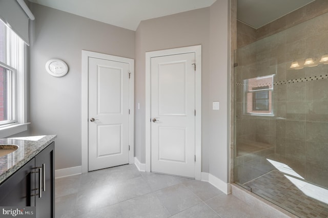 full bath featuring tile patterned flooring, a shower stall, vanity, and baseboards