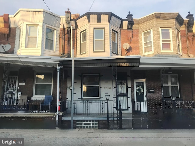 townhome / multi-family property with covered porch and brick siding