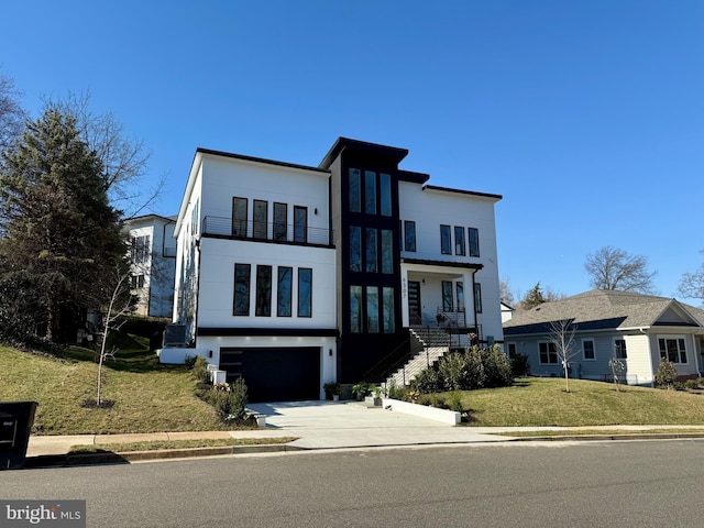 contemporary home with concrete driveway, a balcony, an attached garage, a front lawn, and stucco siding